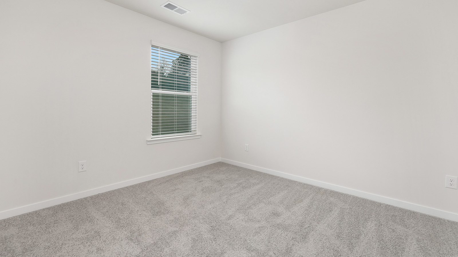 Model carpeted bedroom with small window