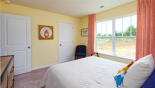 Model carpeted bedroom with large window