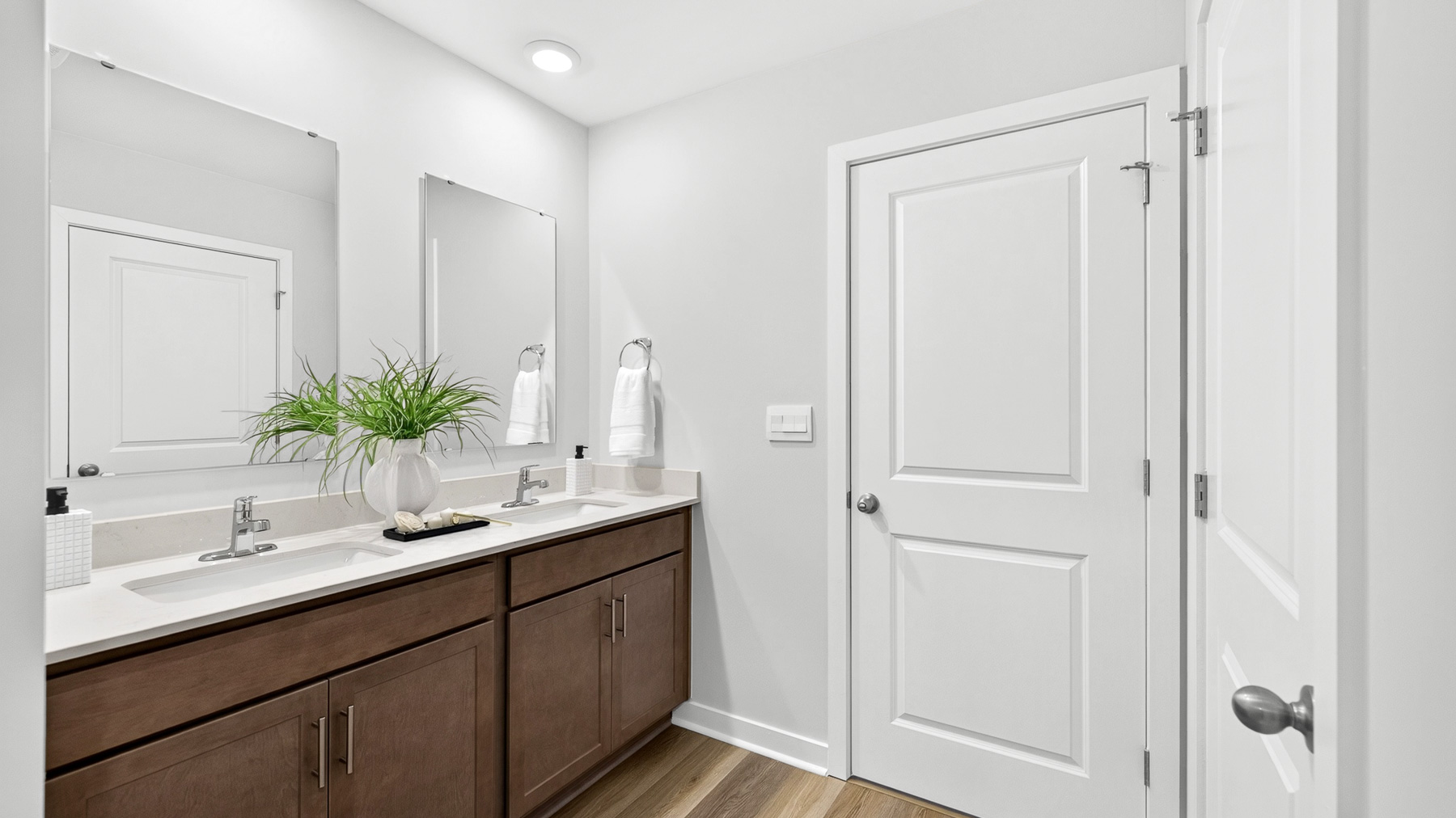 Primary bathroom with brown cabinets and standing glass shower