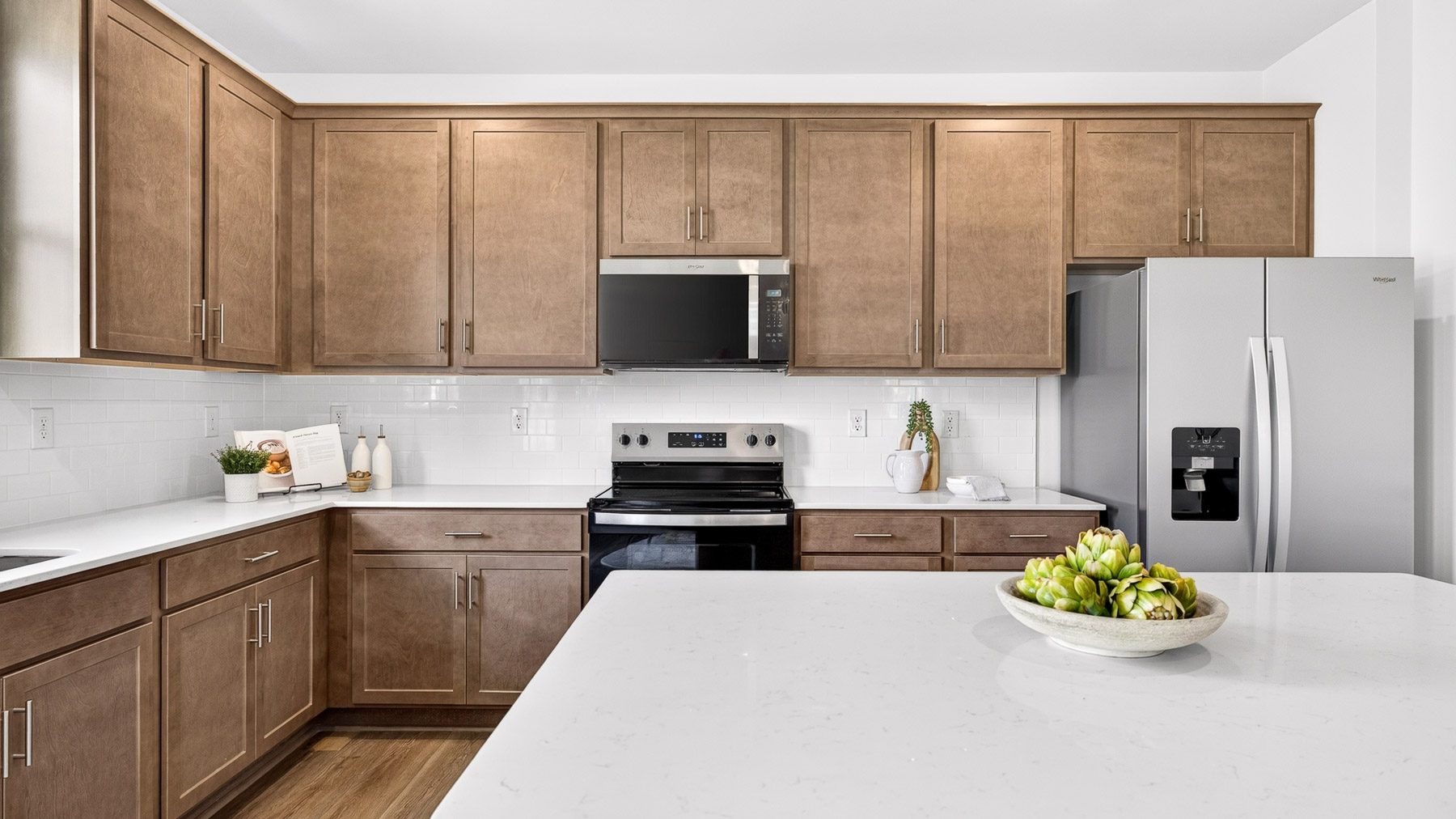Kitchen and island with brown cabinets and stainless steel appliances