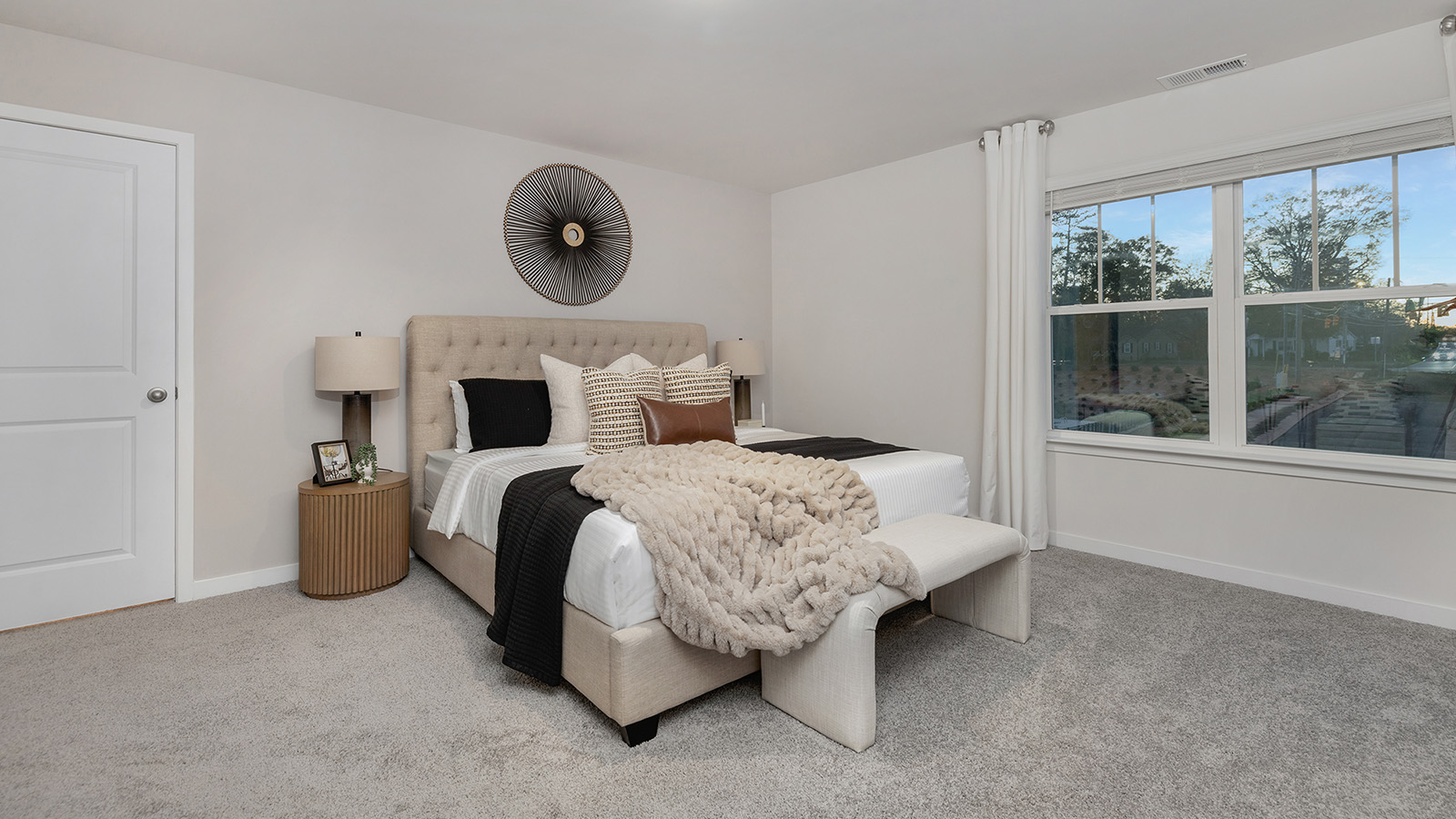 Carpeted bedroom with large window, view of bathroom door