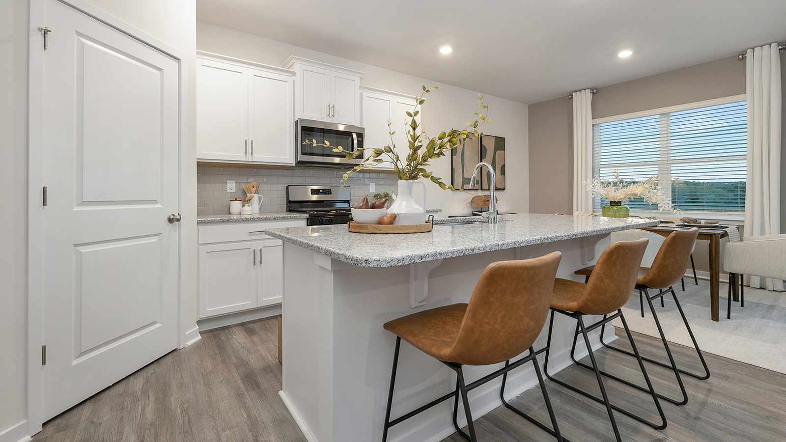 Open concept kitchen with large island bar and white cabinets and countertops and stainless steel appliances