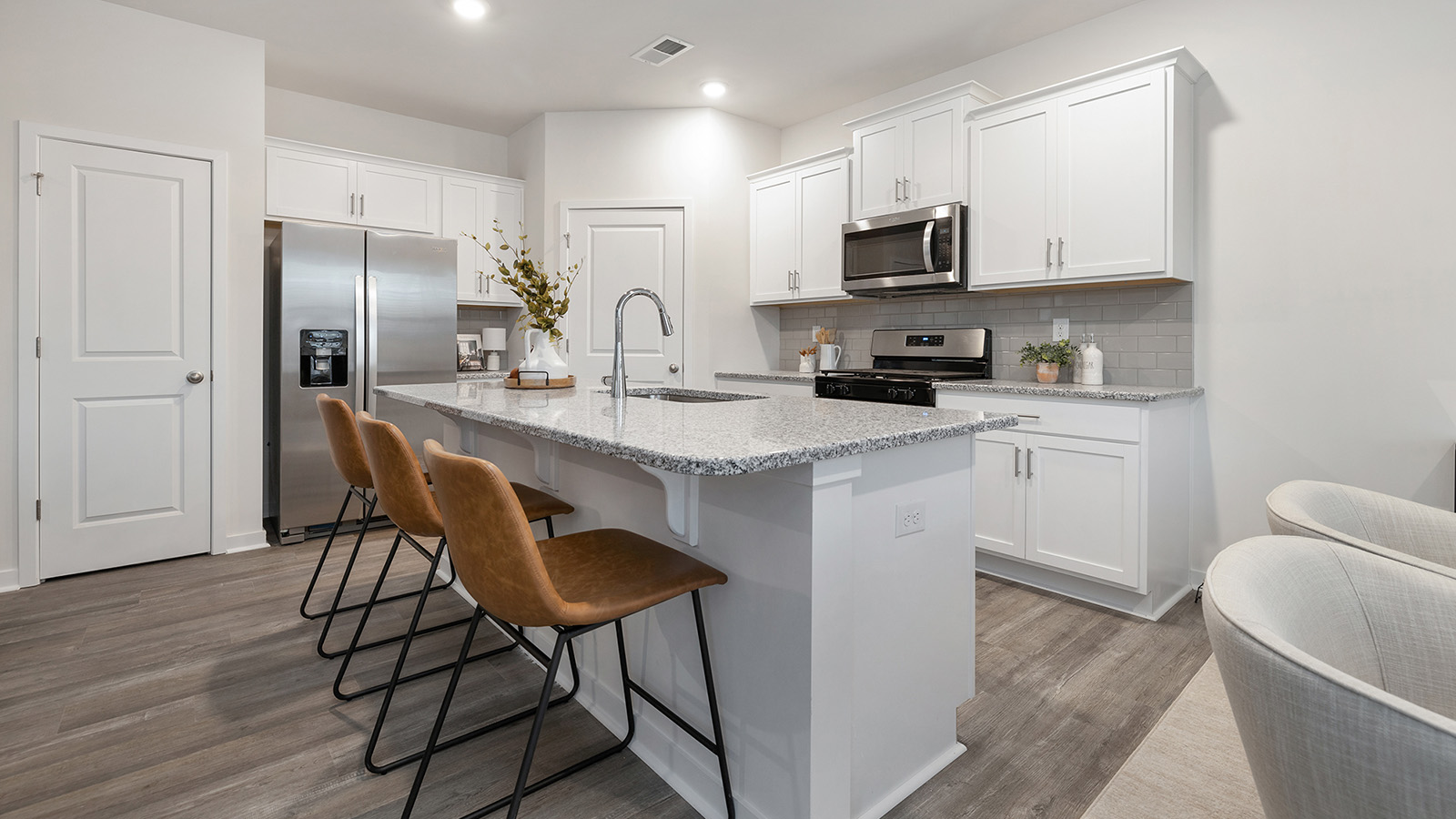 Kitchen and island with white cabinets, quartz counters, wood floors and stainless steel appliances