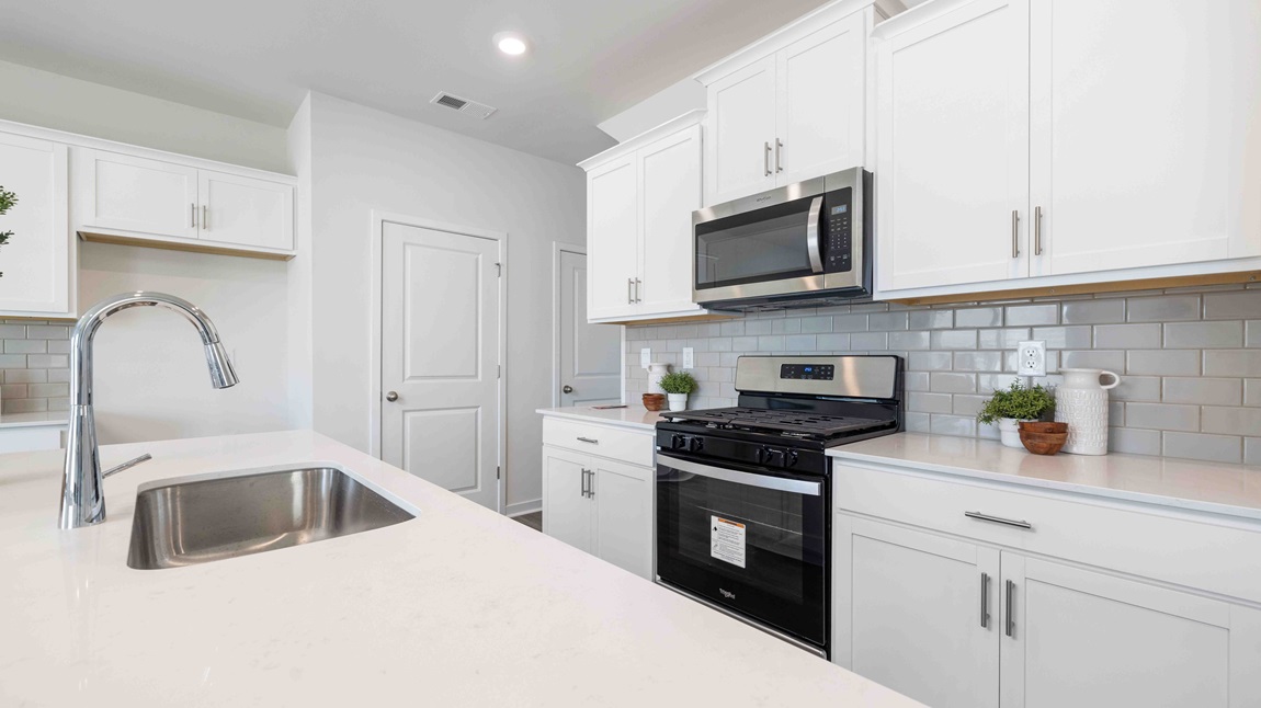 Kitchen and island, white cabinets, wood floors, and stainless steel appliances