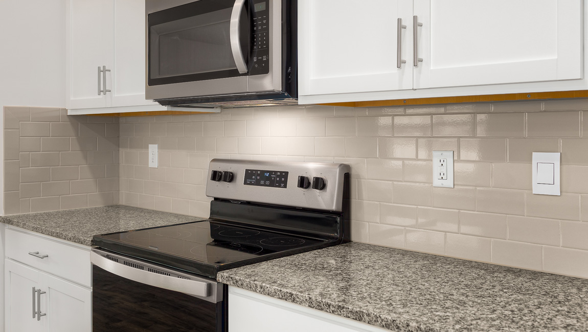 Kitchen and island, white cabinets, wood floors, and stainless steel appliances