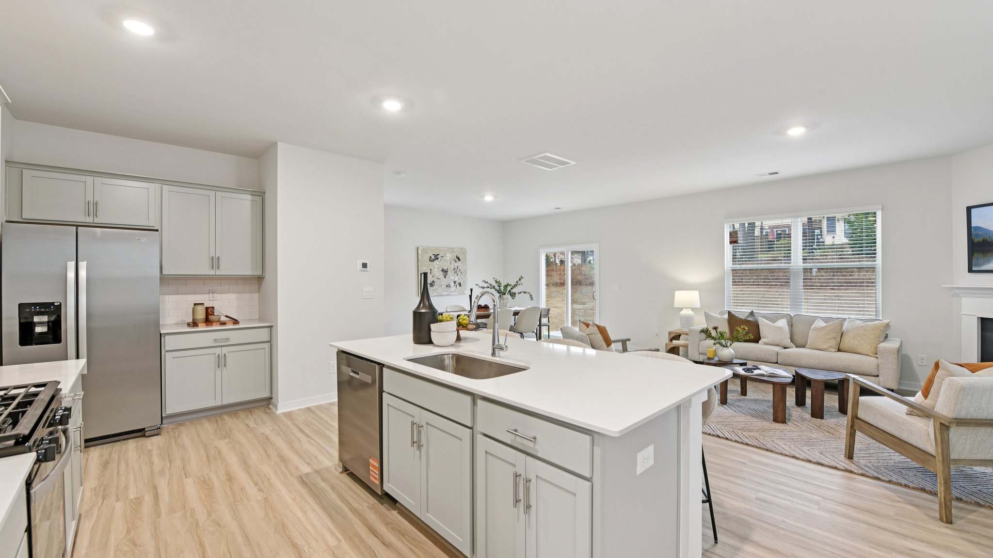 Kitchen and island with white cabinets, white subway tile backsplash and stainless steel appliances