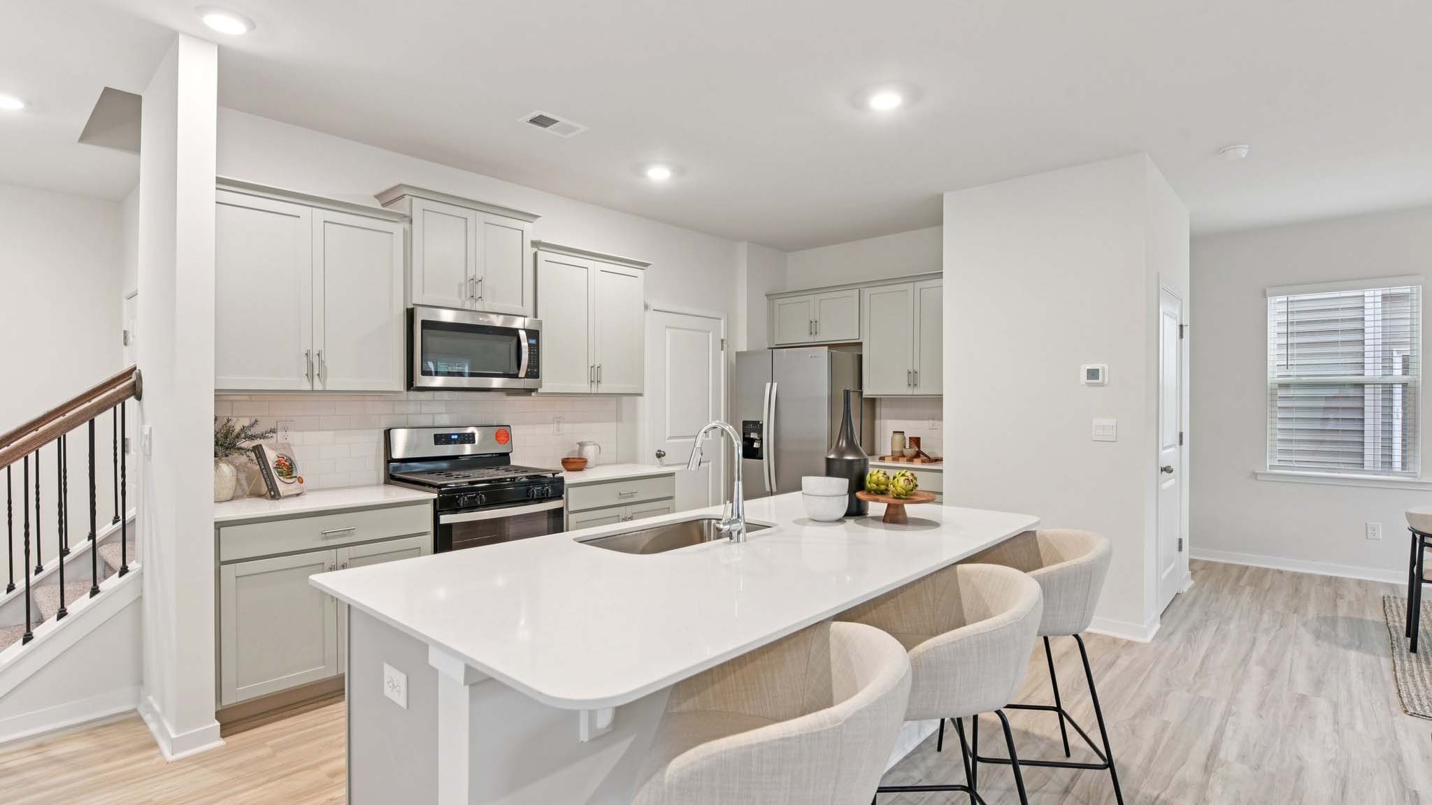 Kitchen and island with white cabinets, white subway tile backsplash and stainless steel appliances