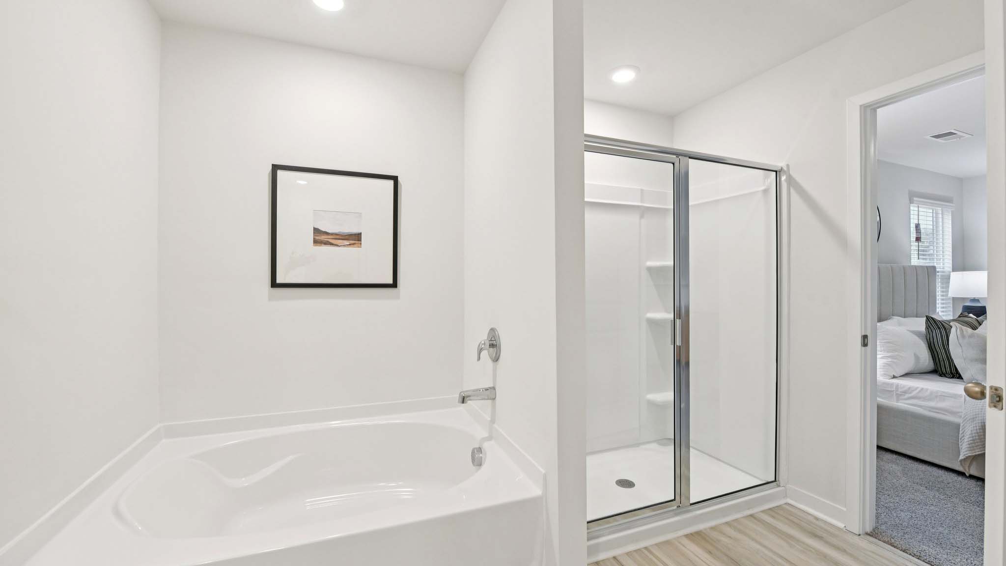 Primary bathroom with double sinks, white cabinets and glass door shower