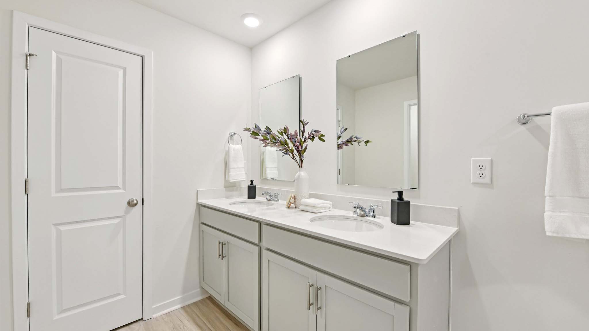 Primary bathroom with double sinks, white cabinets and glass door shower