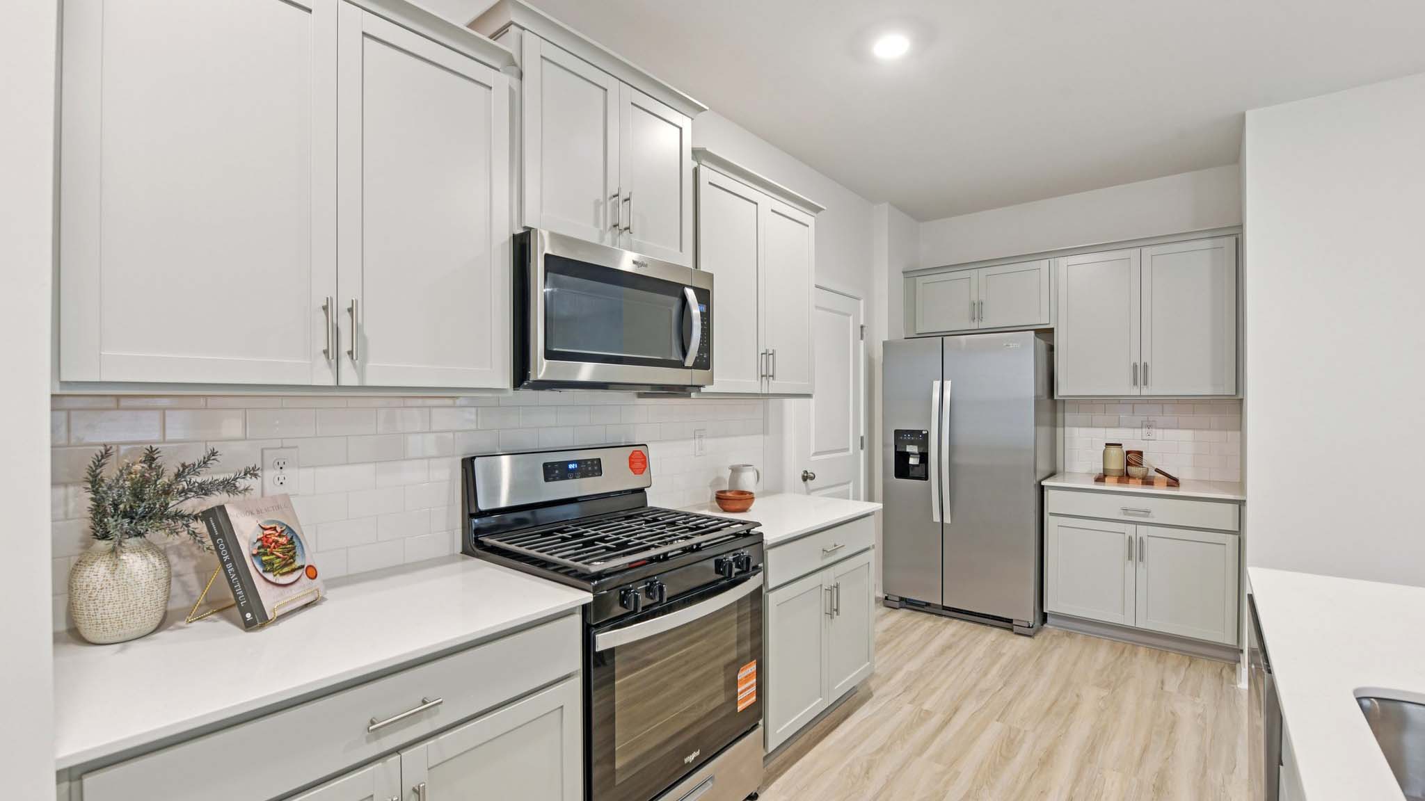 Kitchen and island with white cabinets, white subway tile backsplash and stainless steel appliances