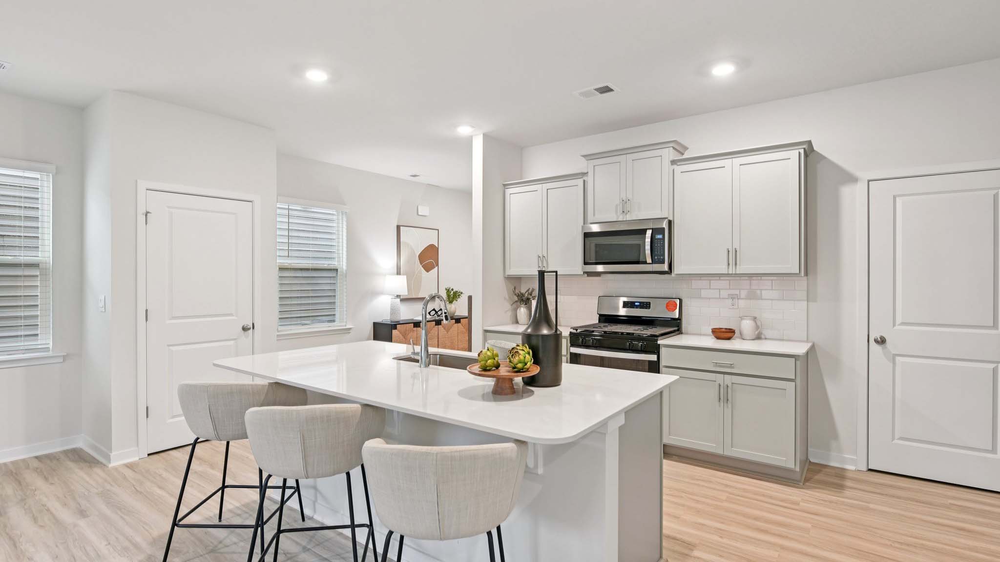 Kitchen and island with white cabinets, white subway tile backsplash and stainless steel appliances
