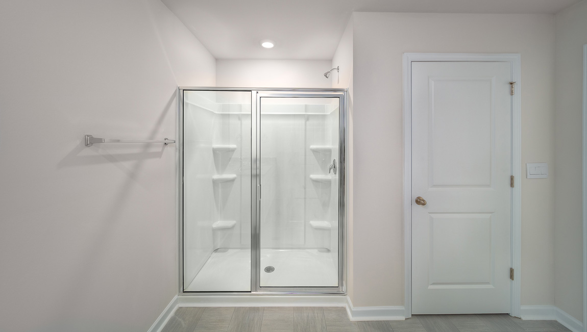 Primary bathroom with double sinks, white cabinets and glass door shower