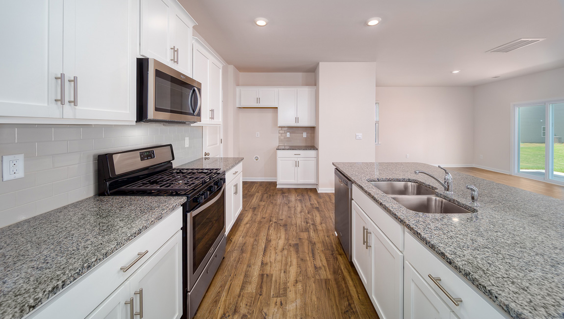 Kitchen and island with white cabinets, white subway tile backsplash and stainless steel appliances