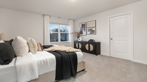 Primary bedroom carpeted with large window