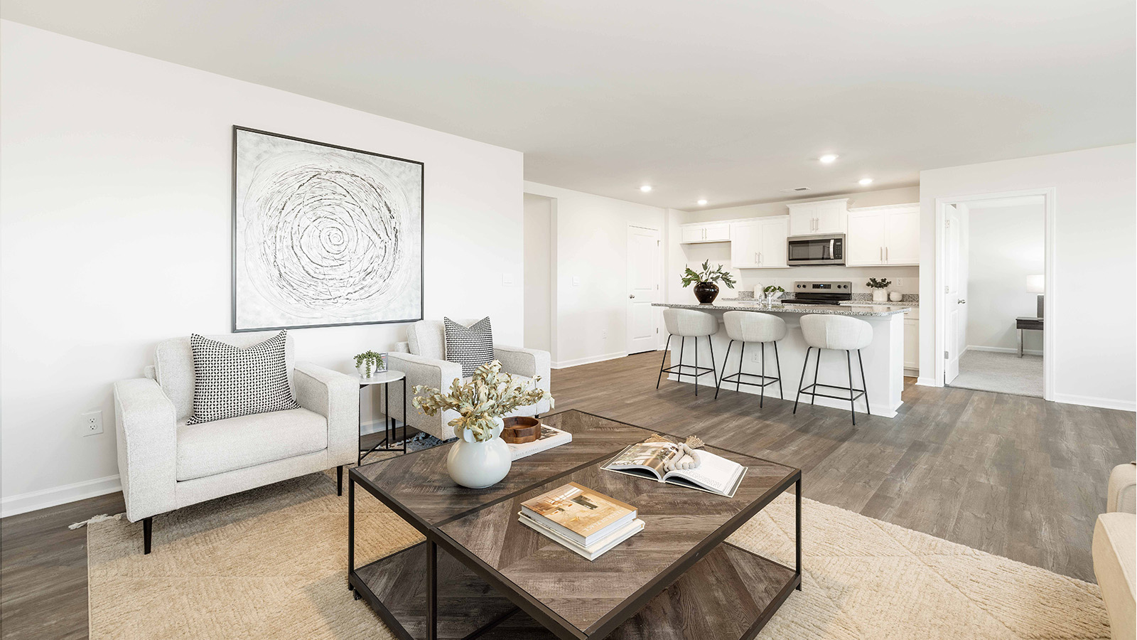 Modern open-concept living room with wood floors, and a fireplace, located beside kitchen