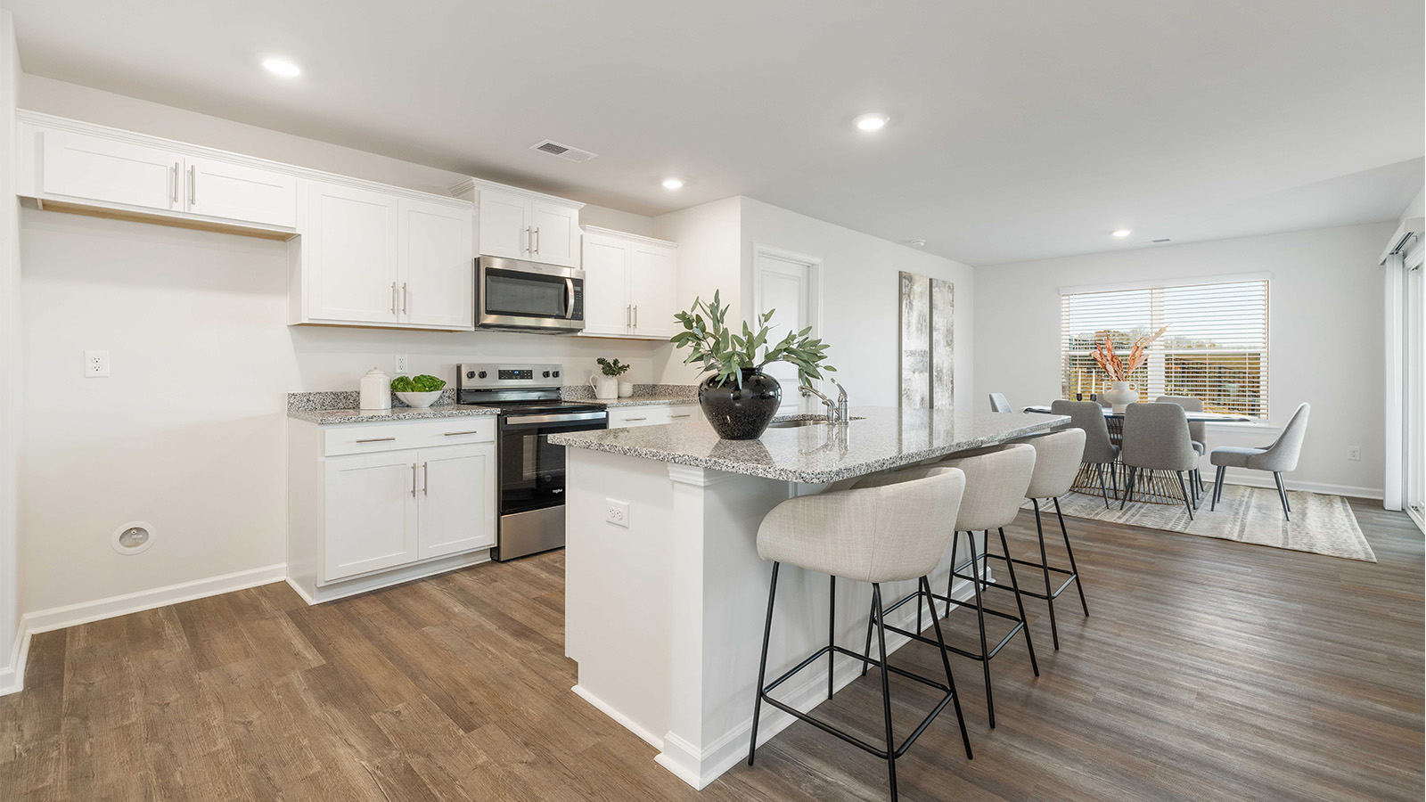 Kitchen and island with white cabinets, quarts countertops, wood floors, and stainless steel appliances