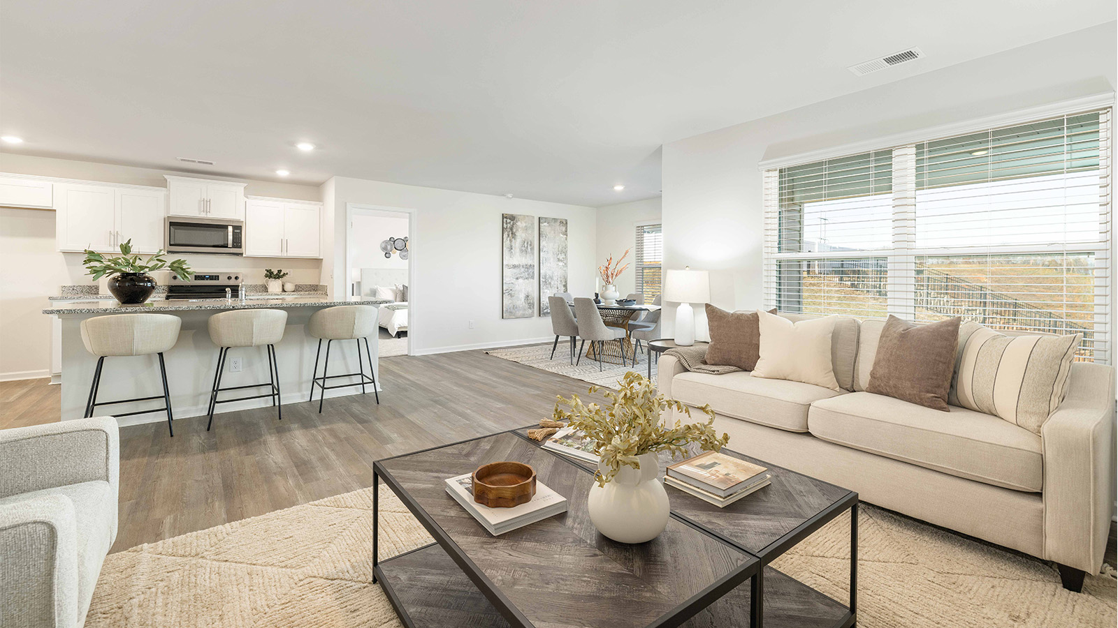 Modern open-concept living room with wood floors, and a fireplace, located beside kitchen