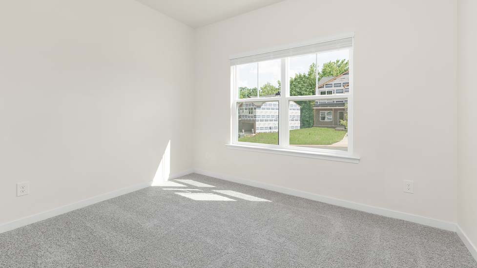 Carpeted bedroom with small window, being used as an office
