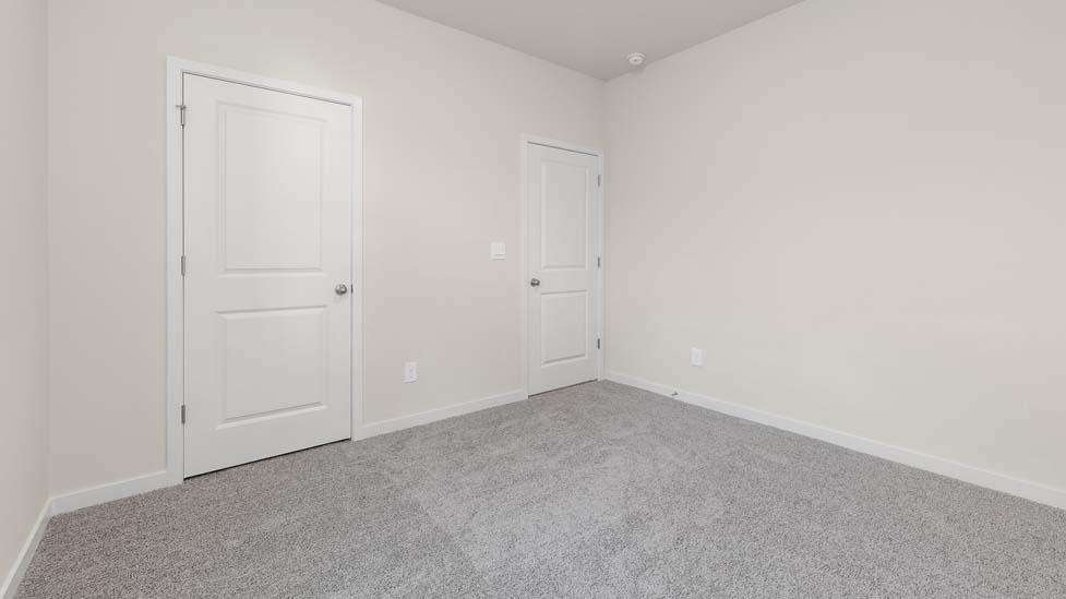 Carpeted bedroom with small window, being used as an office