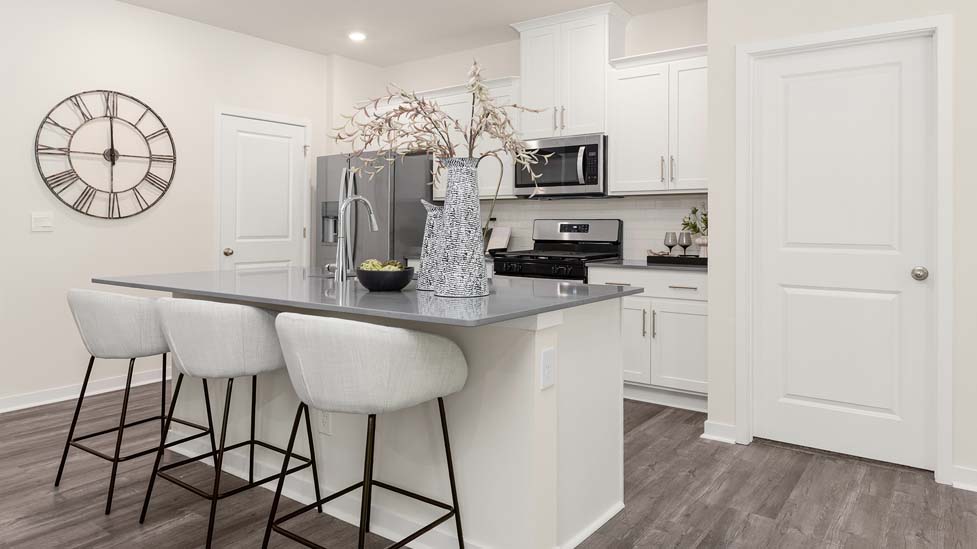 Kitchen and island with white cabinets, quarts countertops, wood floors, and stainless steel appliances