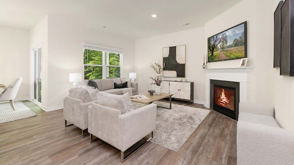 Modern open-concept living room with wood floors, and a fireplace, located beside kitchen