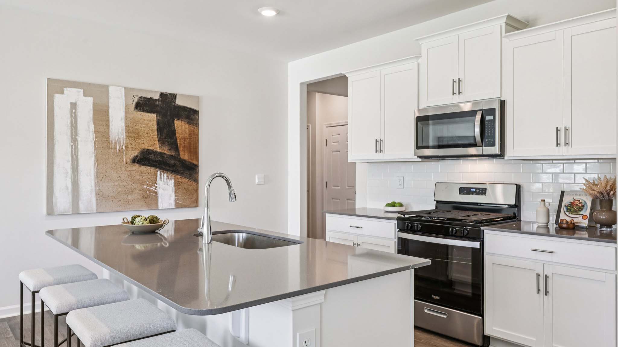 Kitchen and island with white cabinets and subway tiles and stainless steel subway tiles