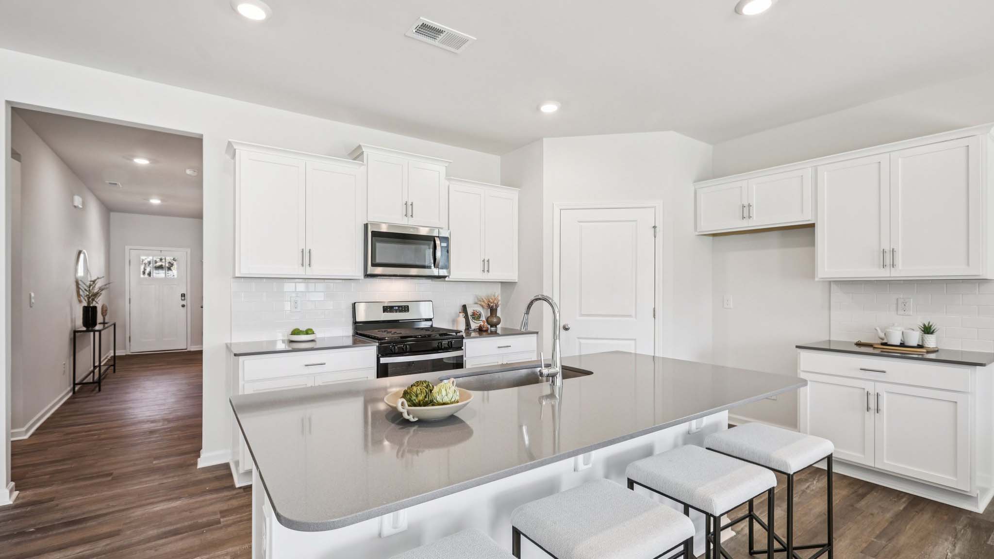 Kitchen and island with white cabinets and subway tiles and stainless steel subway tiles