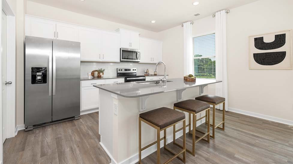 Kitchen and island with white cabinets and windows