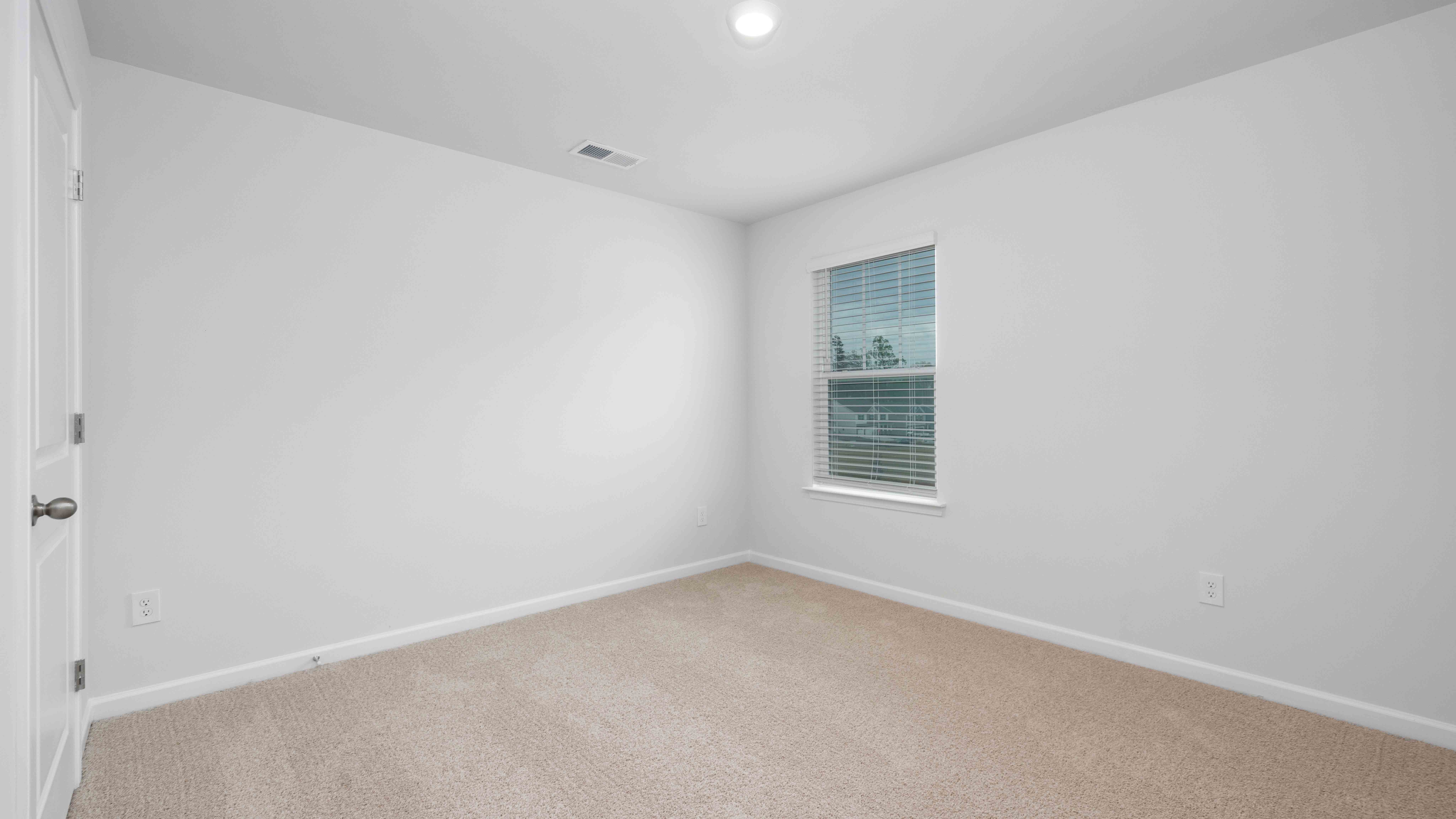 Model carpeted bedroom with small window