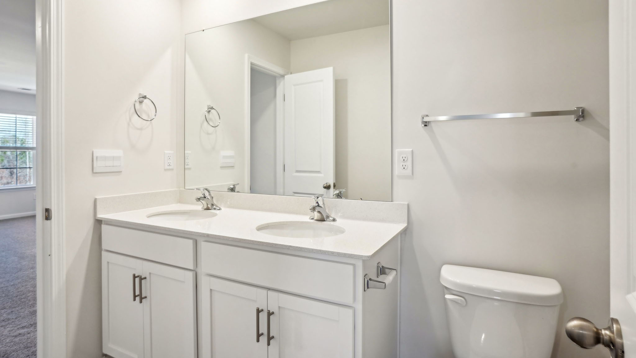 Bathroom with double sinks, bathtub, and white cabinets and counters