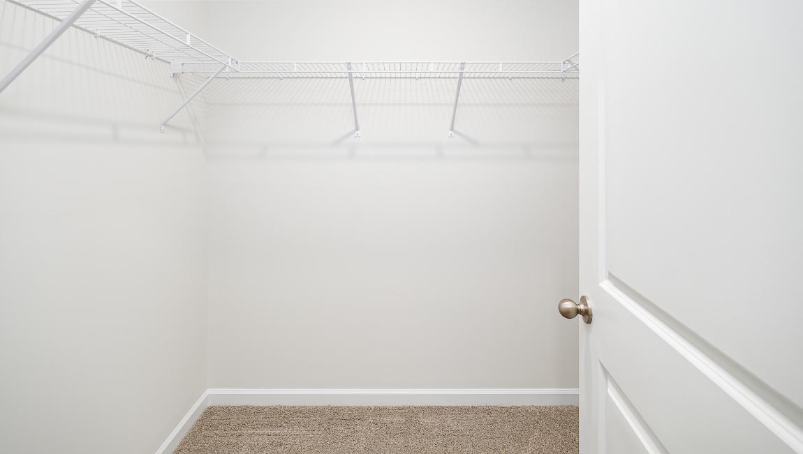 Carpeted walk in closet with hanging racks