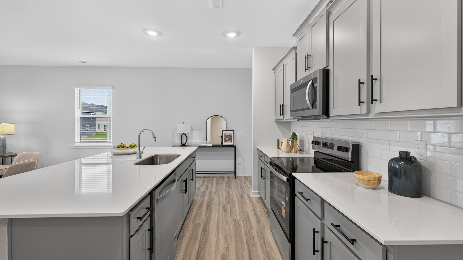 Kitchen with island, white cabinets, vinyl floors, and stainless steel appliances
