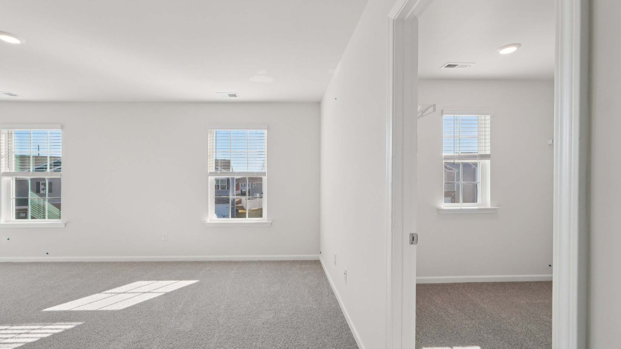 Primary carpeted bedroom with windows