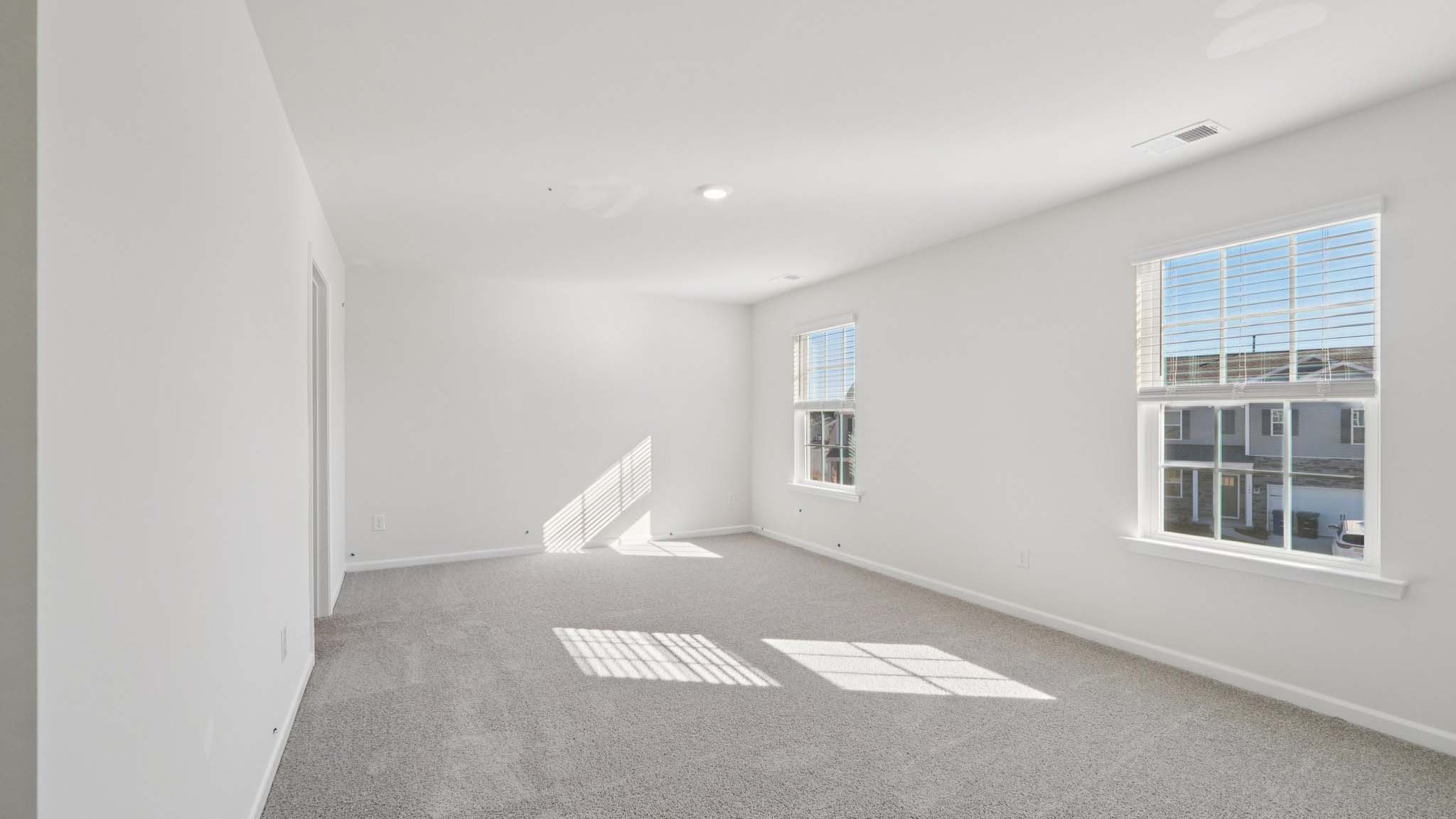 Primary carpeted bedroom with windows