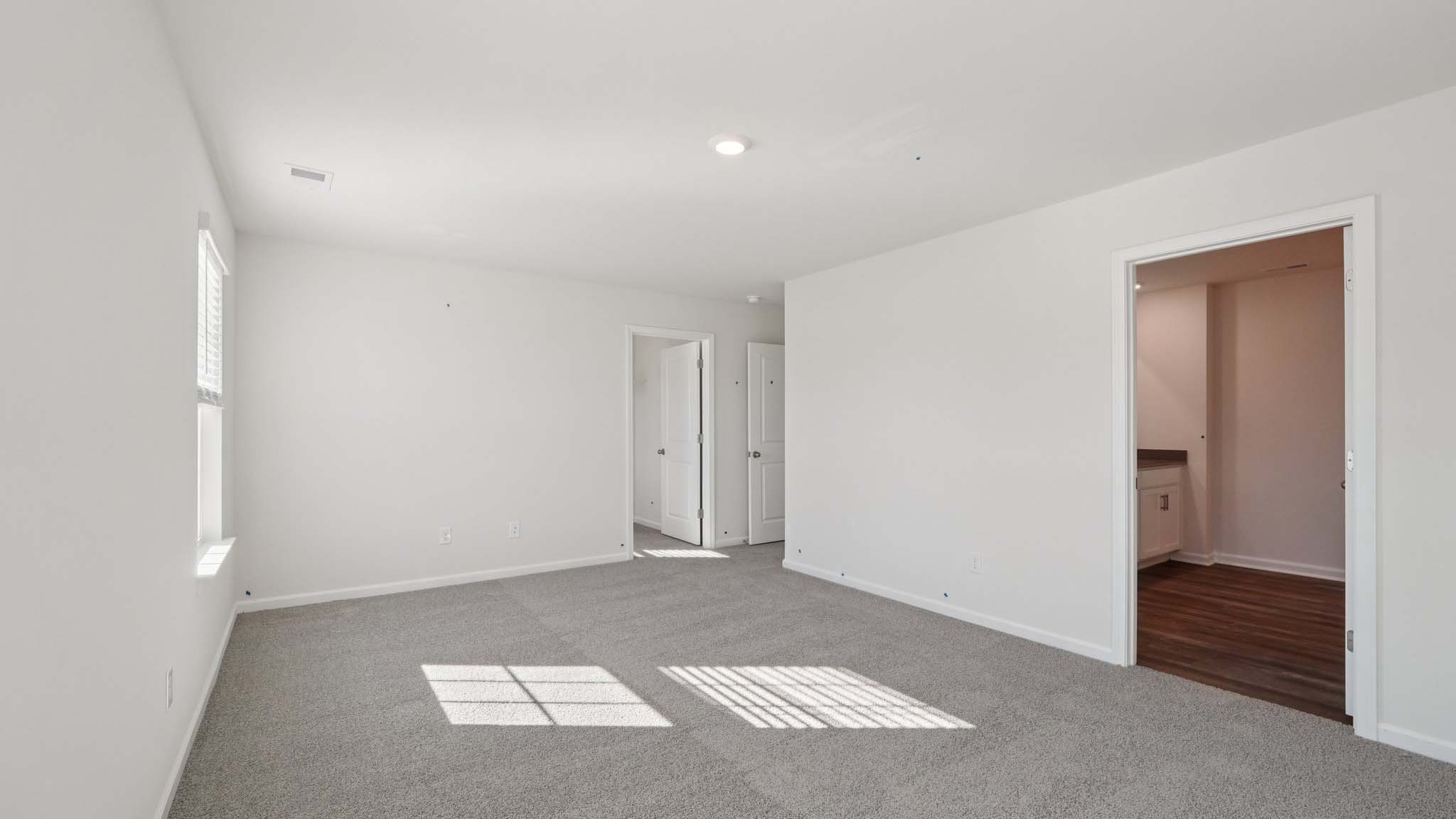 Primary carpeted bedroom with windows