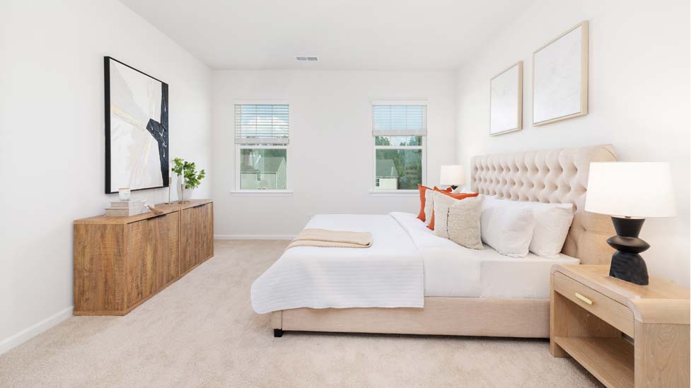 Primary bedroom with carpet and two large windows