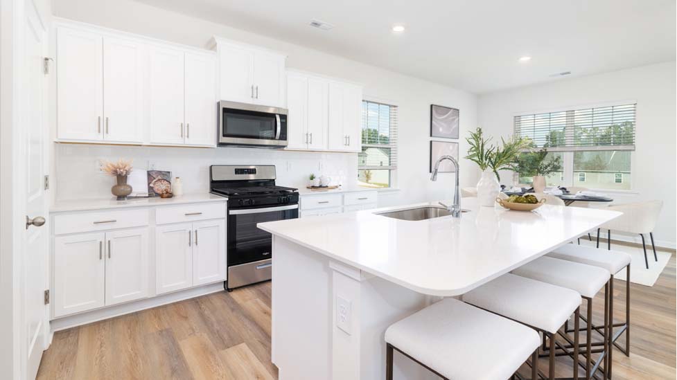 Kitchen and island with quartz countertops, white cabinets, and stainless steel appliances