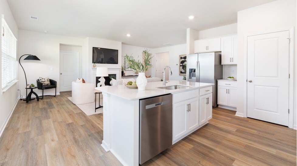 Kitchen and island with quartz countertops, white cabinets, and stainless steel appliances