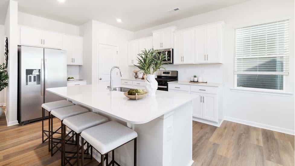 Kitchen and island with quartz countertops, white cabinets, and stainless steel appliances