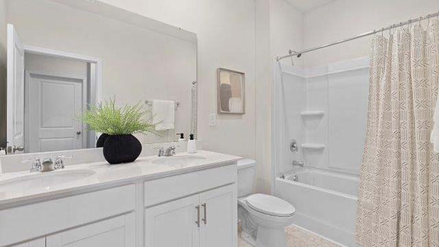 Bathroom with white counters and cabinets, and glass door shower