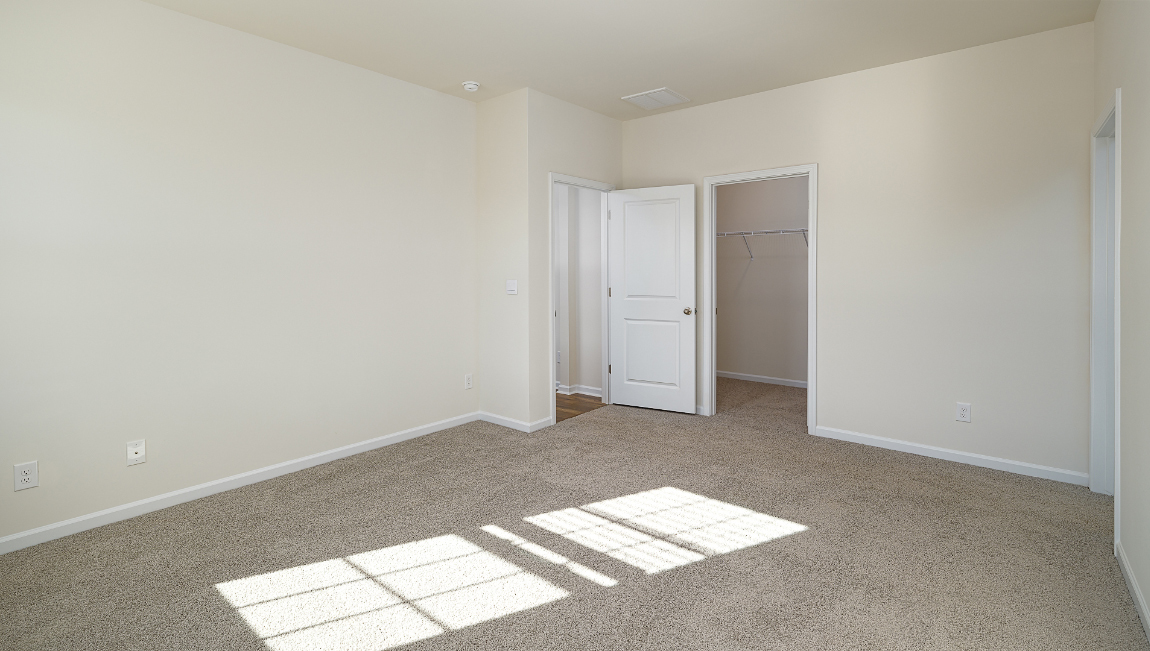 Primary bedroom with carpet and two large windows