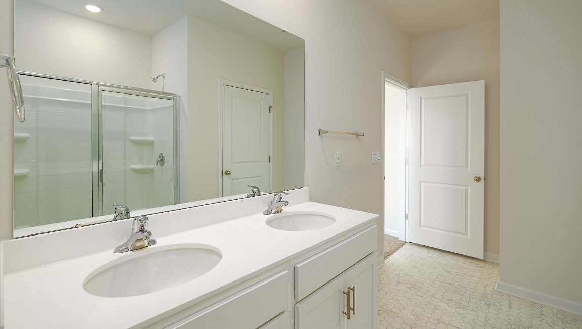 Bathroom with white counters and cabinets, and glass door shower