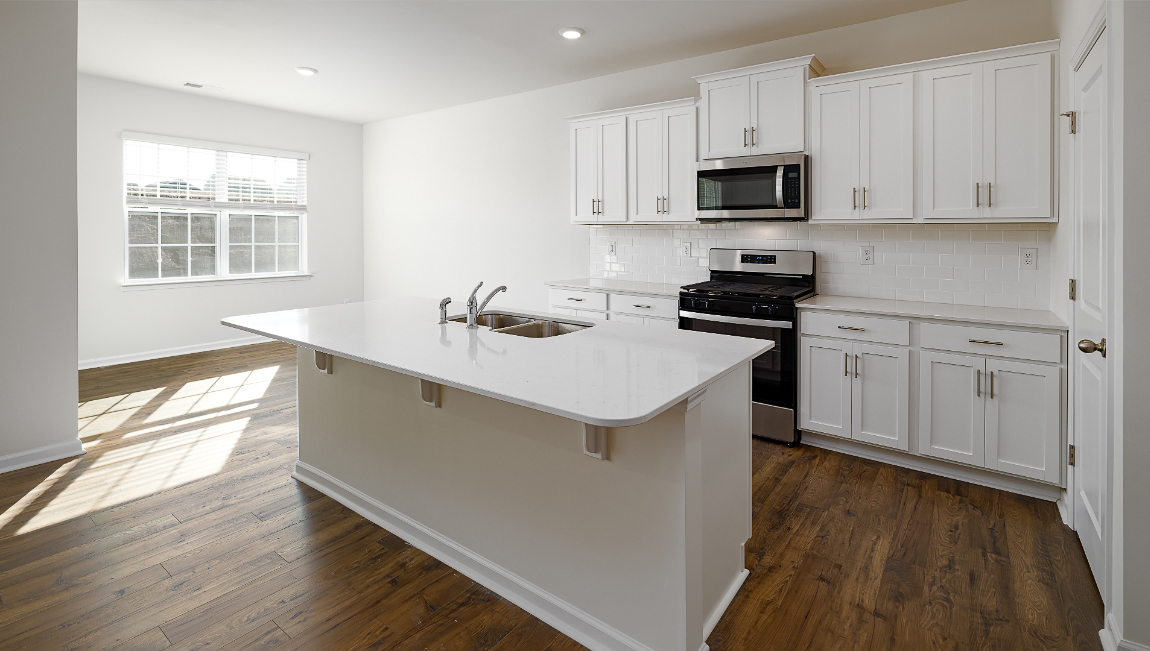 Kitchen and island with quartz countertops, white cabinets, and stainless steel appliances