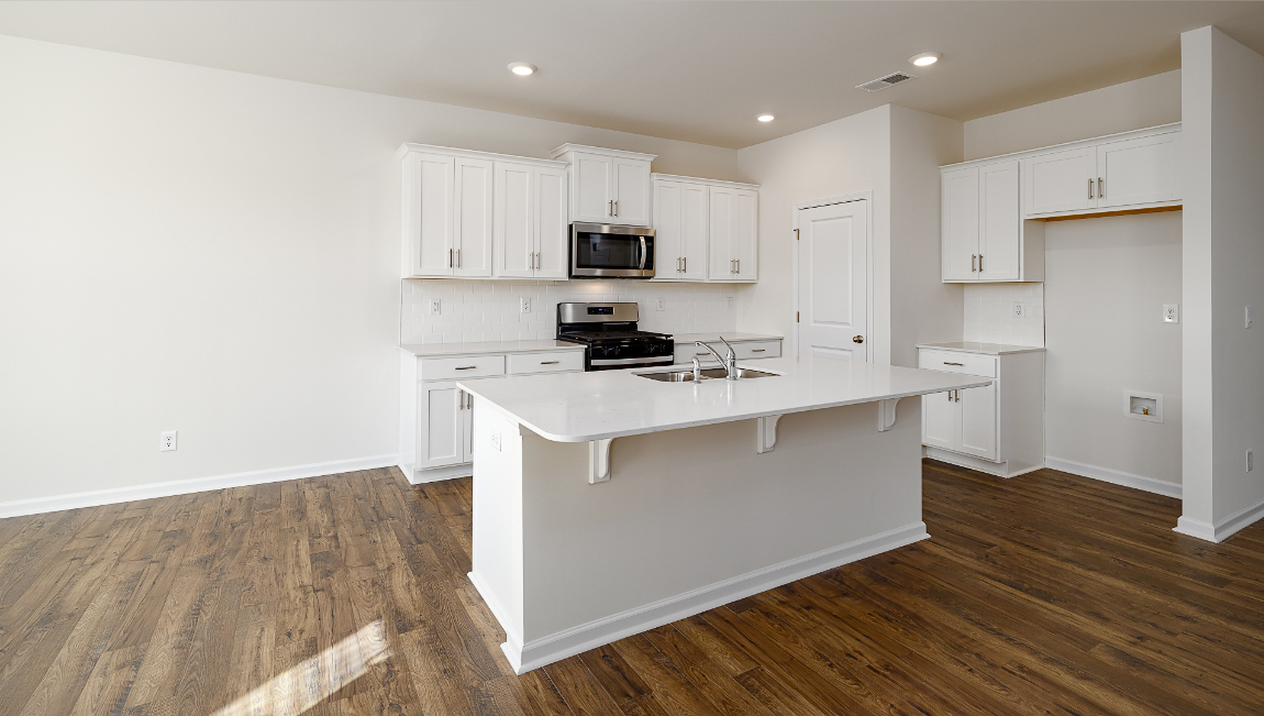 Kitchen and island with quartz countertops, white cabinets, and stainless steel appliances