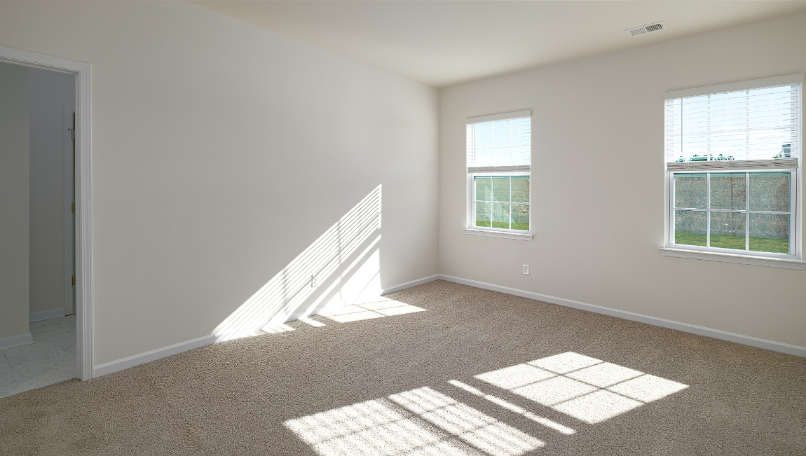 Primary bedroom with carpet and two large windows