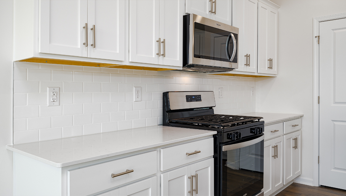 Kitchen and island with quartz countertops, white cabinets, and stainless steel appliances