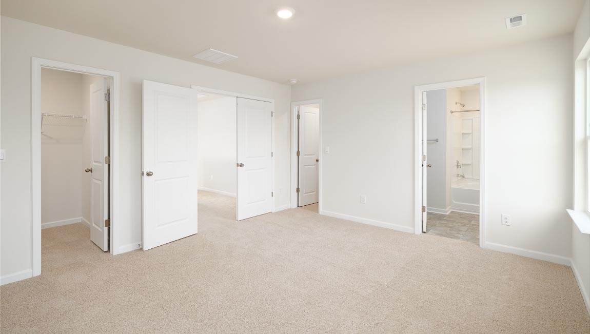 Carpeted primary bedroom with two small windows