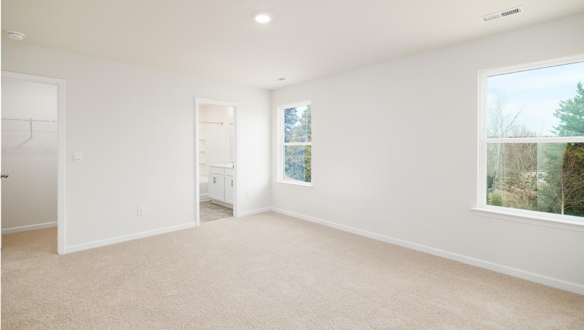 Carpeted primary bedroom with two small windows