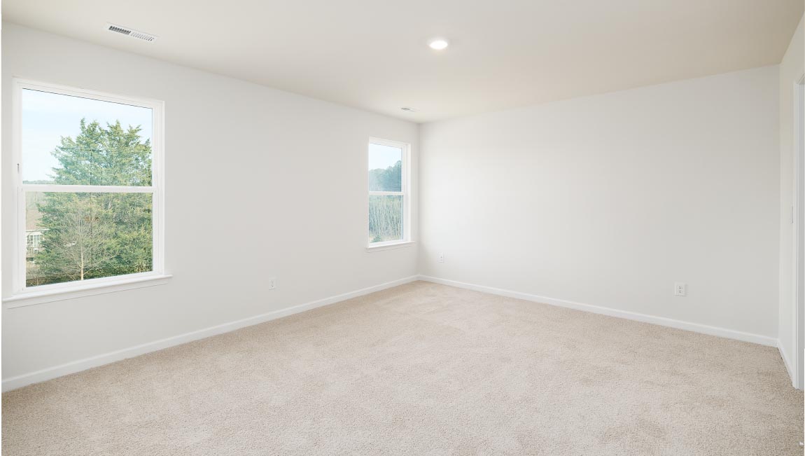 Carpeted primary bedroom with two small windows