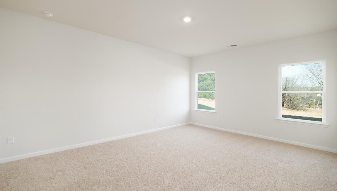 Carpeted primary bedroom with two small windows